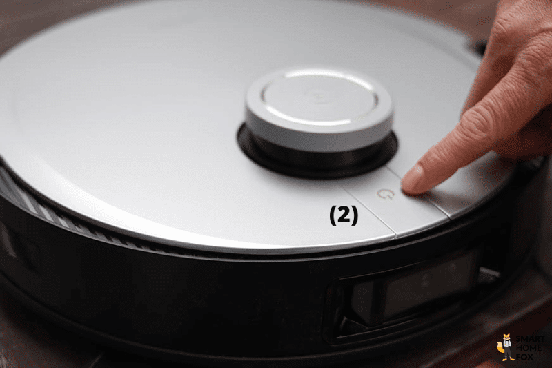 Der Steuerknopf am Deebot X1 Saugroboter wird mit dem Finger angetippt